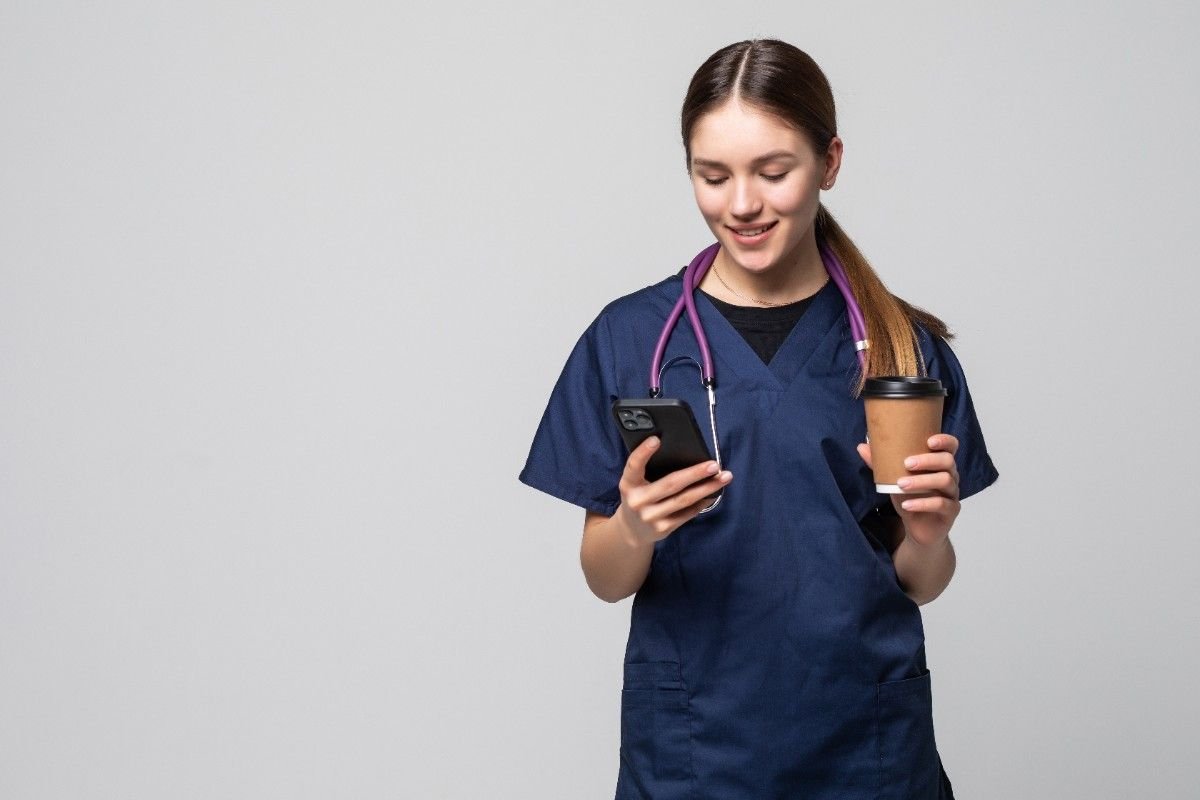 female-doctor-sitting-with-mobile-phone-drinking-coffee-isolated-white (1)